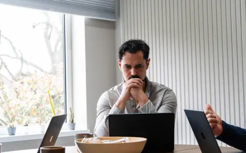 Man denkt diep na over beleid en maatschappij, omringd door laptops en plantjes.