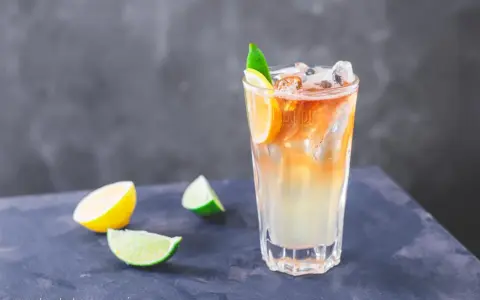 Orzeźwiający drink Long Island Iced Tea z plasterkami cytryny i limonki, idealny na upalne dni.