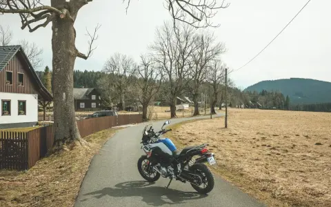 Motocykl czeka na jednodniowy wypad motocyklowy. W tle wiejskie domki i puste pola.