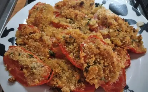 Pomodori gratinati al forno, un piatto semplice e gustoso, con una croccante panatura dorata e erbe aromatiche.