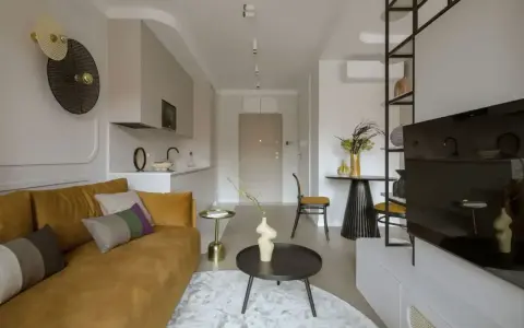 Nowoczesny salon z kanapą w kolorze musztardowym, tworzącą ciepłą paletę kolorów ziemi.