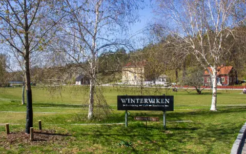 Vinterviken Stockholm, en grönskande park med träd och byggnader. En skylt visar "Winterviken - Festvåning - Café - Konferens".