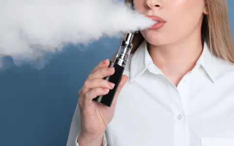Mujer exhala vapor de un vaper, una alternativa moderna al tabaco tradicional.