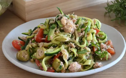 Deliziosa insalata di zucchine a spirale con tonno, pomodorini e olive verdi, un piatto fresco e leggero.