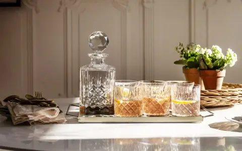 Elegancka karafka i szklanki z drinkami, idealne do degustacji whisky. Z czym pić whisky? Z cytryną i lodem, w dobrym towarzystwie.