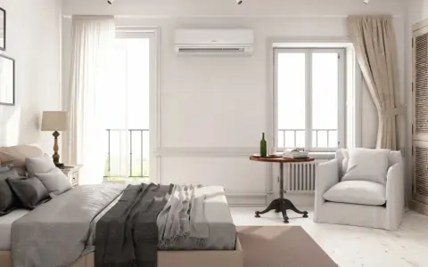 Un dormitorio luminoso con cama, armario de madera y aire acondicionado. La unidad de aire acondicionado está colocada estratégicamente en la pared, mostrando dónde colocar el aire acondicionado en un dormitorio para una climatización óptima.