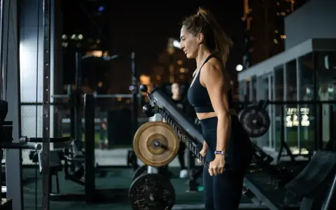 Kobieta ćwiczy na siłowni, korzystając z wyciągu. Jej karta multisport pozwala na takie wieczorne treningi.