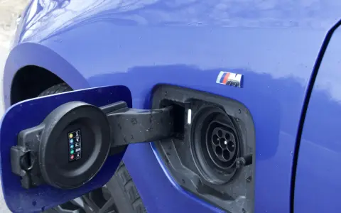 Niebieskie BMW 330e z otwartą klapką gniazda ładowania.