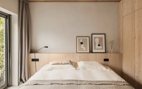 Acogedor dormitorio sin cabecero, con cama de lino, arte abstracto y armario de madera.