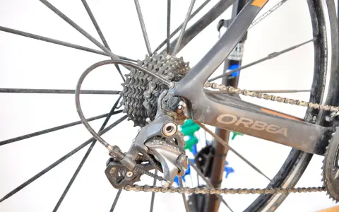 Tylna przerzutka Shimano Ultegra, kluczowy element przekładni rowerowej, na tle koła i ramy Orbea.