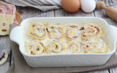 Nidi di rondine in una teglia bianca, con prosciutto, formaggio e funghi. Ingredienti per un piatto delizioso.