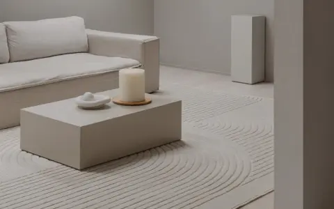 Salon w odcieniach ivory: sofa, stolik kawowy, świeca i dywan z geometrycznym wzorem tworzą spokojną aranżację.