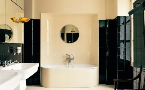 Élégante salle de bain noir et blanc avec baignoire îlot, lavabo double vasque et carrelage brillant.