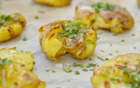 Krispiga smashed potatoes med ost och persilja, redo att serveras.