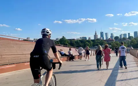 Rowerzysta na moście w Warszawie, w tle panorama miasta. Idealne miejsce na odkrywanie tras rowerowych Warszawa i okolice.