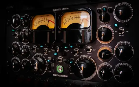 Panneau de compresseur mastering avec deux VU-mètres lumineux. Apprenez comment utiliser un compresseur en ajustant les nombreux boutons et sélecteurs.