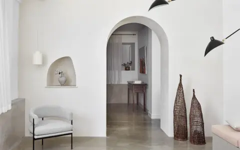 Un salon moderne avec un arche en pierre, un fauteuil gris, des lampes noires et un habillage arche maison.