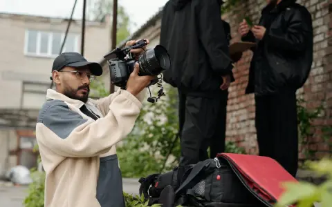 Regista con telecamera in mano, intento a catturare l'essenza di un film d'autore. Sullo sfondo, due uomini discutono.