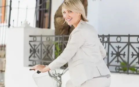 Donna sorridente in bicicletta, con un elegante outfit che valorizza la sua figura. Un look chic per una donna di 45 anni.
