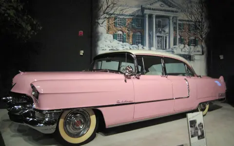 Ein rosafarbener Cadillac, der einst Elvis Presley gehörte, steht vor einer gemalten Kulisse von Graceland.