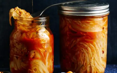 Zwei Gläser mit fermentiertem Chinakohl, bereit für das authentische kimchi rezept original. Ein Löffel ragt aus dem linken Glas.