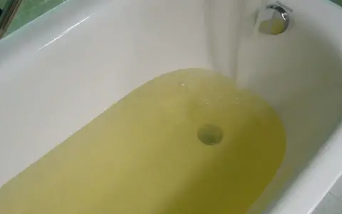Wanna z żółtą wodą, z kranu leje się woda.