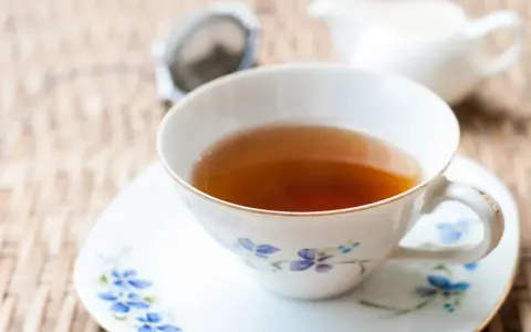 Aromaticzna herbata Earl Grey, znana ze swoich właściwości pobudzających i relaksujących, w eleganckiej filiżance z niebieskimi kwiatami.