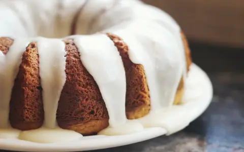 Gâteau moulé, doré, nappé d'un glaçage blanc crémeux. Une invitation à découvrir comment faire du fondant blanc.