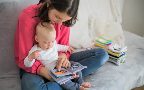 Mama czyta dziecku książeczkę o samochodach. Wycofane dziecko, przyczyny jego nieśmiałości mogą być różne, ale wspólne czytanie buduje więź.