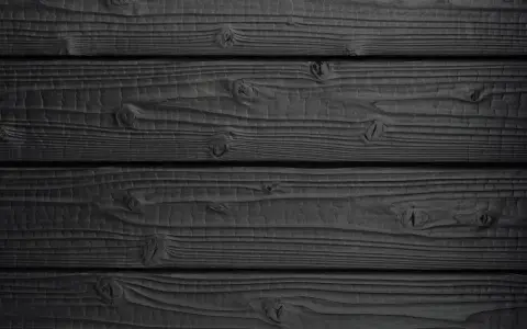 Tavolato scuro, con venature evidenti e nodi che emergono dal **legno bruciato**.