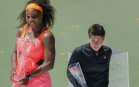 Serena Williams, con su impresionante altura, celebra con un trofeo. A su lado, otra tenista recibe su premio.