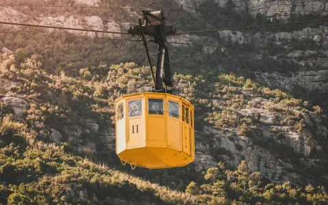 A yellow cable car ascends the rugged slopes of Montserrat.