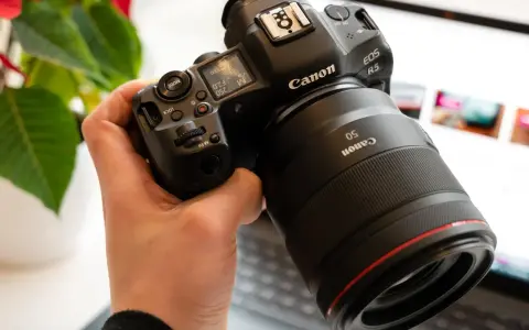 Dłoń trzyma aparat Canon R5 z obiektywem 50mm. Trwa test możliwości sprzętu.