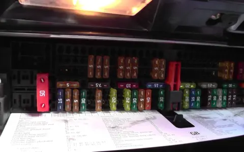 Panel z bezpiecznikami BMW E46, z czerwonym bezpiecznikiem 50A i innymi o różnej wartości.
