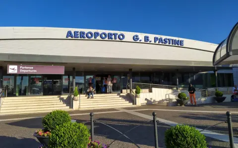 Wejście do Aeroportu G.B. Pastine w Rzymie Ciampino. Słoneczny dzień, ludzie czekają na odloty.