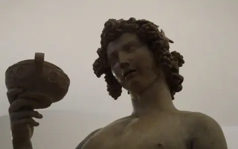 Bacchus, jeune dieu du vin, couronné de grappes, tient une coupe. Une œuvre d'art inspirée par Michel-Ange.