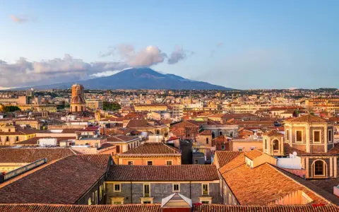 Vista panoramica di Catania con l'Etna sullo sfondo. Tetti rossi, cupole e palazzi storici offrono spunti per le cose da fare a Catania.