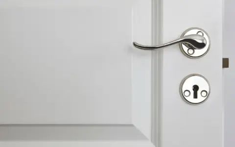 Eleganckie, chromowane klamki do białych drzwi, idealnie komponujące się z klasycznym wnętrzem.