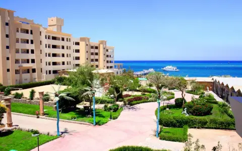 Piękny widok na **King Tut Resort** z basenem, palmami i morzem w tle.