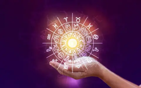 Obracający się znak zodiaku nad dłonią, zapowiadający horoskop na weekend.