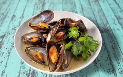Un plat de moules au roquefort, garni de persil frais, baignant dans une sauce crémeuse.
