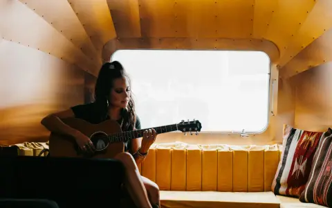 Sarah Jones, piosenkarka, gra na gitarze w przytulnym wnętrzu.