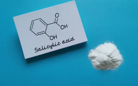 Karta z wzorem chemicznym kwasu salicylowego i jego proszkiem. Dowiedz się, jak stosować kwas salicylowy.