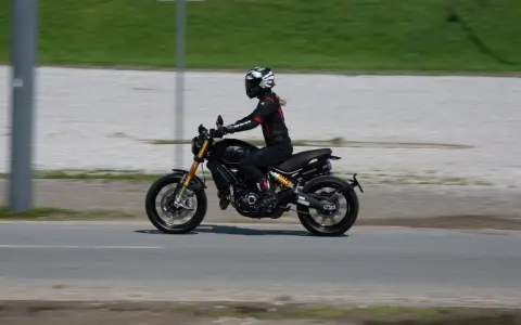 Kobieta w kasku i kombinezonie jedzie motocyklem spełniającym normę **euro 4**.
