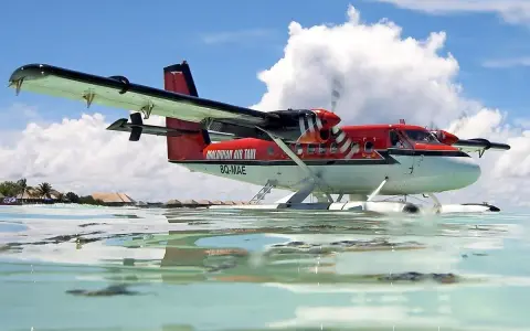 Ein rotes Twin Otter Flugzeug schwimmt auf dem Wasser vor den Malediven.