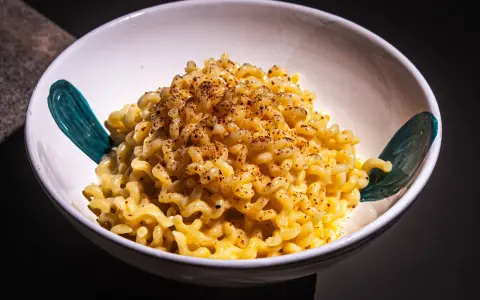 Cremige Pasta Alfredo, bestreut mit Gewürzen, in einer weißen Schüssel mit türkisfarbenen Akzenten.