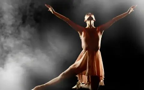 En ballerina i en ljusrosa klänning utför en graciös rörelse i klassisk balett, omgiven av dramatisk rök och ljus.