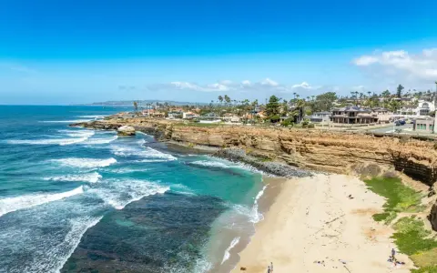 Traumhafte Küste in San Diego mit türkisfarbenem Wasser, sandigem Strand und Villen auf den Klippen.