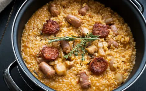 Arroz a la zamorana en paellera con chorizo, salchichas y hierbas aromáticas.