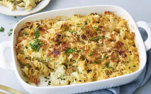 Herzhafter Blumenkohl Auflauf mit Nudeln und knuspriger Käsekruste, garniert mit frischer Petersilie. Ein Genuss für die ganze Familie.